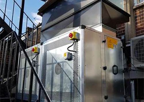 A large air handling unit containing woods air movement fans installed on the roof of a Greek restaurant