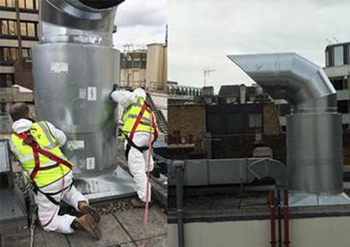 Workmen installing a kitchen extraction fan on the roof of a restaurant
