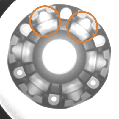 An x ray of a fan component with a an orange circle highlighting an imperfection