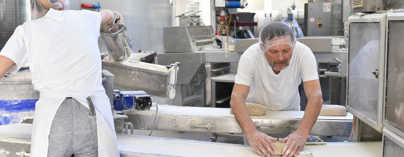 A banner photo of two workers in a floury commercial bakery to show that ATEX can be be in dusty environments.