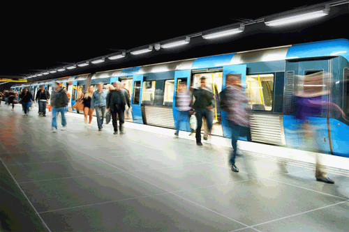 A stock image of an underground train at a station with people walking along the platform